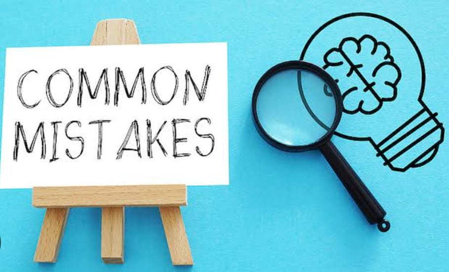 The image shows a small wooden easel with a white paper on it that says "COMMON MISTAKES" in handwritten-style black text. Next to the easel on the right is a drawing of a lightbulb with a brain inside it, and a magnifying glass is placed over the brain part of the lightbulb drawing. The background of the image is sky blue.