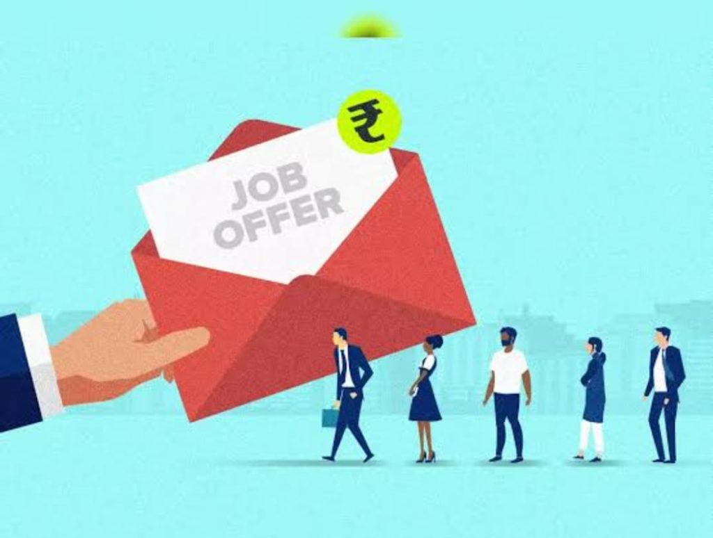 The image shows a graphic of a hand holding a red envelope with a "JOB OFFER" letter inside. A green circle with a rupee symbol ₹ is on the top right corner of the envelope. Five people in business attire are standing in front of a city skyline in the background. The scene is set against a light blue background.