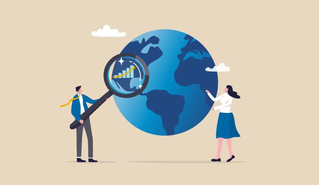 The image shows a cartoon illustration of a man and a woman standing next to a large blue globe.

- The man is on the left, wearing a blue jacket, white shirt, gray pants, and black shoes. He's holding a giant magnifying glass up to the globe.
- Inside the magnifying glass is a bar graph with a yellow line trending upwards.
- The woman is on the right, wearing a white top, blue skirt, and black shoes. She's touching the globe.
- There are two small white clouds above the globe.
- The background of the image is beige.